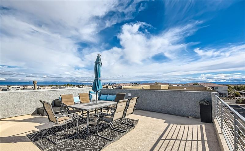Private rooftop deck with outdoor dining set and umbrella overlooking the valley